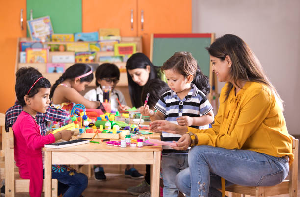 Preschool children doing painting with teacher in art class